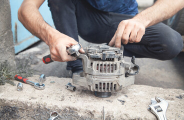Man repairs car alternator. Service center