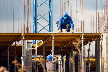 Real construction worker working on a high building and leveling floor for cementing.