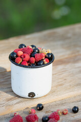 Berry fruits like strawberries, red currants, raspberries and black currants on wood table with copyspace. Selective focus