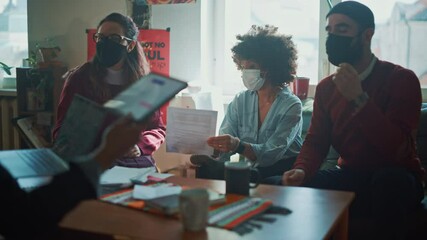 Team of Young People Wearing Face Masks, Talking on a Meeting in Modern Creative Office. Team of Social Media Marketing Professionals Brainstorm, Share Data on Tablet Computer. Slow Motion Medium Shot - Powered by Adobe