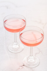 Two glasses of pink rose wine on white marble background