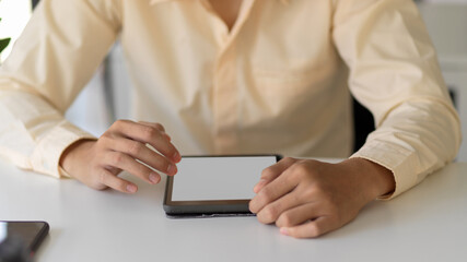 Businessperson hands working with mock-up tablet on simple office desk