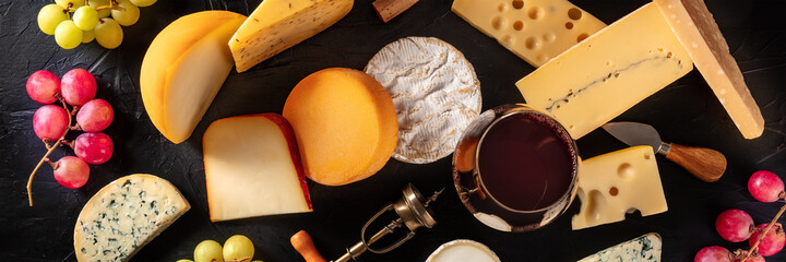 Cheese and wine panorama, top shot on a black background