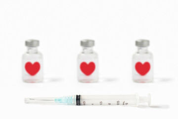 Row of medical vials of injectable medicine with floating hearts and hypodermic needle