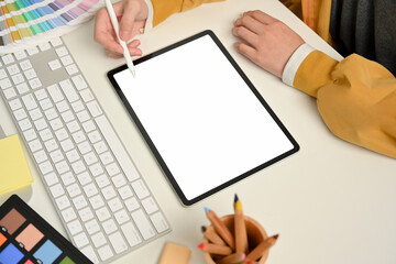 Fototapeta na wymiar Female designer hand working with digital tablet on computer desk with designer supplies