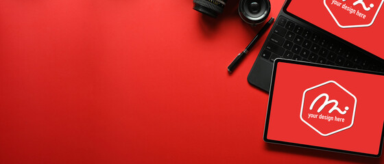 Creative flat lay workspace with two digital tablet, accessories, camera and copy space on red desk