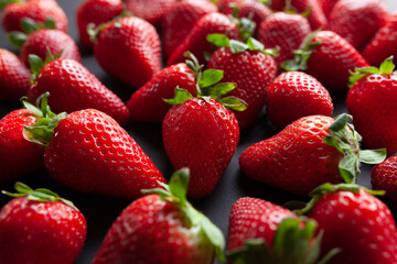Fresh, ripe red strawberries with green leaves on black background