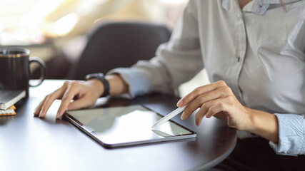Female using mock up blank screen digital tablet while working on her project