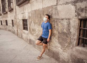 Portrait of young sad man with protective surgical face mask in public spaces in the new normal