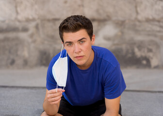 Portrait of young happy man with protective surgical face mask in public spaces in the new normal