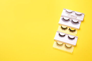 Flat lay composition of professional makeup tools and false eyelashes on bright yellow background, space for text. Concept of make-up artist, beauticisan industry, salon flyer