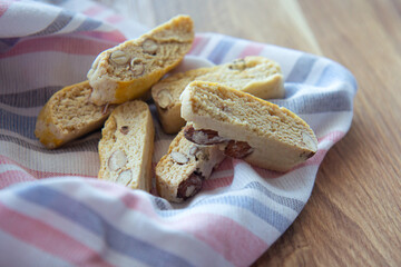 Sweet biscotti cookies with nuts and a striped kitchen towel on wooden background. Side vie