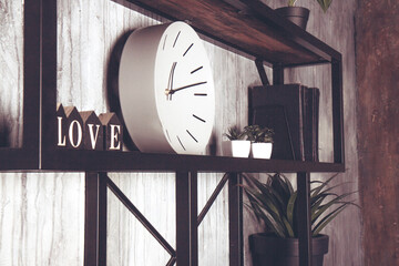 Shabby chic interior decor. White round clock and wooden letters on a vintage shelf. Word love made from wooden cubes. Home space decoration