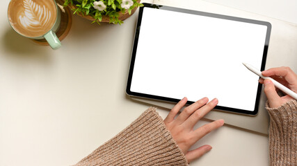 Obraz premium Top view of female hands using mock up digital tablet with stylus pen on white desk