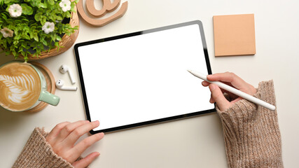 Overhead shot of female hands using mock up digital tablet with stylus pen on white desk