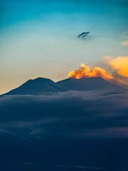The silhouette of Mount Etna smoking in orange by the sunset light 