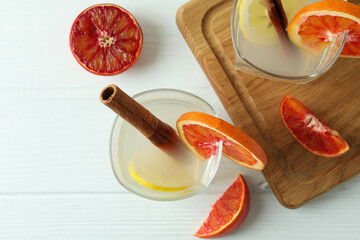 Glasses of cocktail with citrus on white wooden table