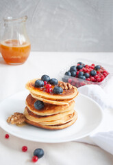 Freshly cooked delicious pancakes with honey, walnut, honey, raspberries and blueberries for breakfast.