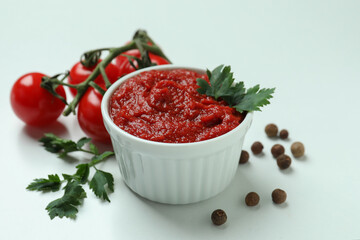 Bowl with tomato paste, tomatoes, pepper and parsley on white background