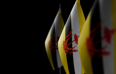Small national flags of the Brunei on a black background