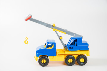 Plastic car. Toy model isolated on a white background. Yellow-blue truck crane with an arrow to lift the load.