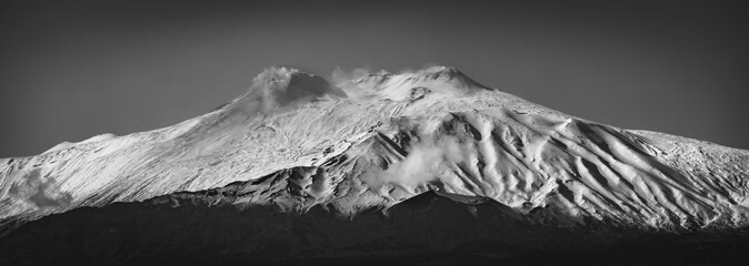 Black and white panorama of Mt. Etna covered by snow. Ash coming from the craters of Mt. Etna