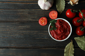 Bowl with tomato paste, tomatoes and garlic on wooden table