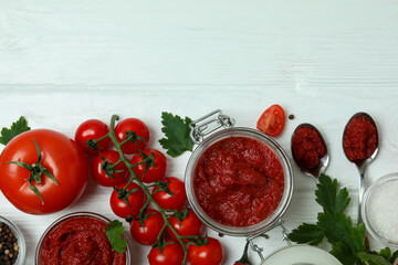 Bowl and jar with tomato paste on white wooden background with ingredients