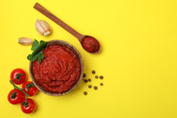 Bowl of tomato paste and ingredients on yellow background