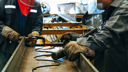 Craftsman cutting steel beam in factory.
