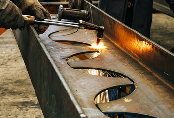 Craftsman cutting steel with sparks fly from gas cutting machine in cellular beam steel fabrication...