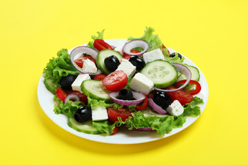 Plate of greek salad on yellow background