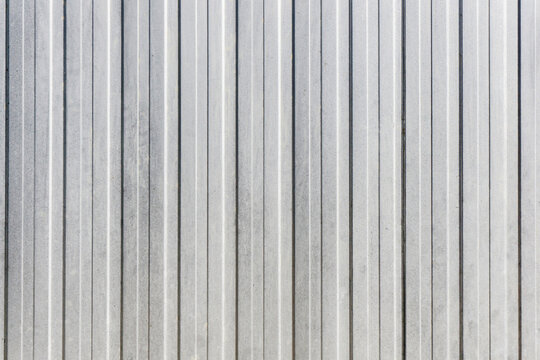 Corrugated metal sheet background. Grunge old grainy metal texture. Silver color industrial pattern. Garage construction gray striped wall. Wavy gray metal background. Metal door siding.
