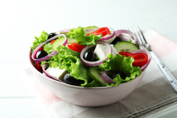 Bowl of greek salad on white wooden background