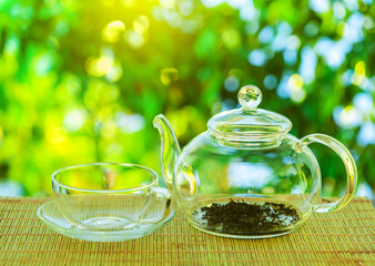 Tea ceremony. An empty glass teapot with tea leaves stands on a wooden table against the background...