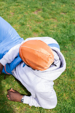 Man wearing organge durag laying in grass