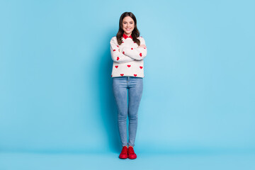 Full length photo of adorable shiny young lady wear hearts print sweater arms crossed isolated blue color background - Powered by Adobe