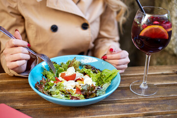 Woman eating salad and drinking sangria at street cafe. Evening relax after hard working day