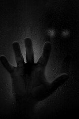 Horror scene of a man with hand against wet shower glass.   Black and white image. Horror concept. Vertical image