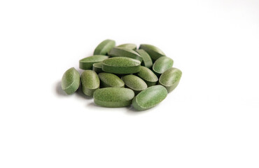 green spirulina pills close up on white background Eco cosmetics concept.