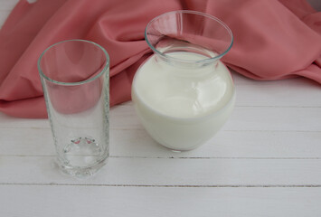 White cow's milk in a clear glass on a light background