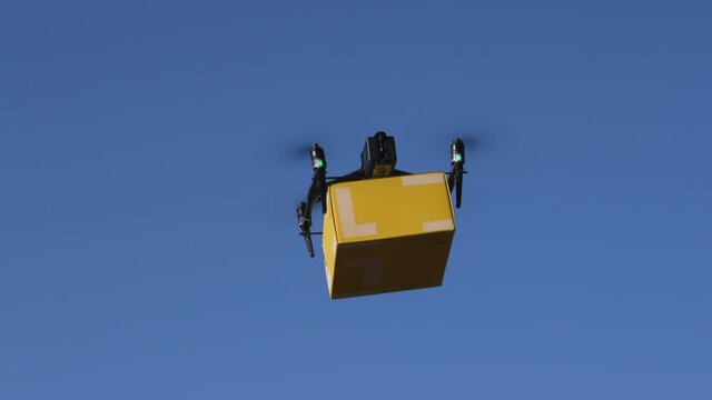 delivery drone carrying parcel flying across the blue sky