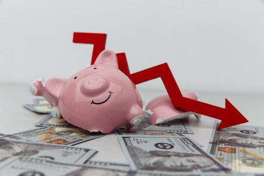 Broken piggy bank and red arrow down with dollar banknotes. Investment and bankruptcy concept