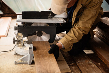 Miter saw with a large metal blade in the hands of a carpenter. Working tool for sawing wooden...