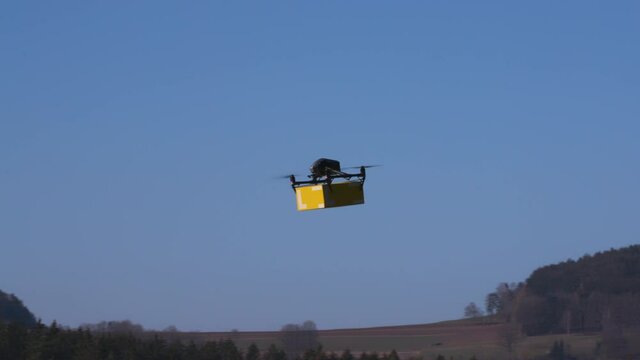 delivery drone carrying parcel flying across the blue sky
