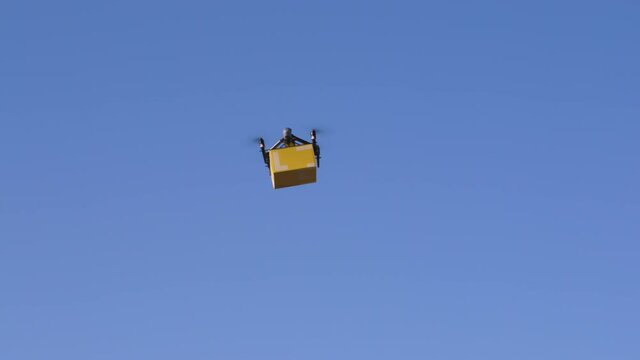 delivery drone carrying parcel flying across the blue sky