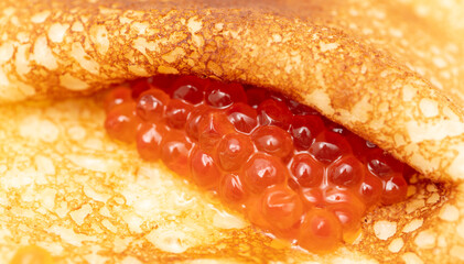 Pancake with red caviar as a background.