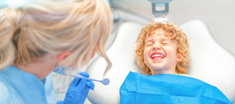 Pretty little boy in dental office, having his teeth checked by female dentist .