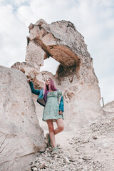 a girl with purple hair in a floral short dress walks on a white mountain