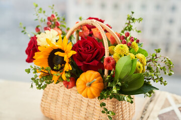 Mixed autumn flowers, sunflower, pumpkin, rose, physalis in basket with album with copy space. High quality photo